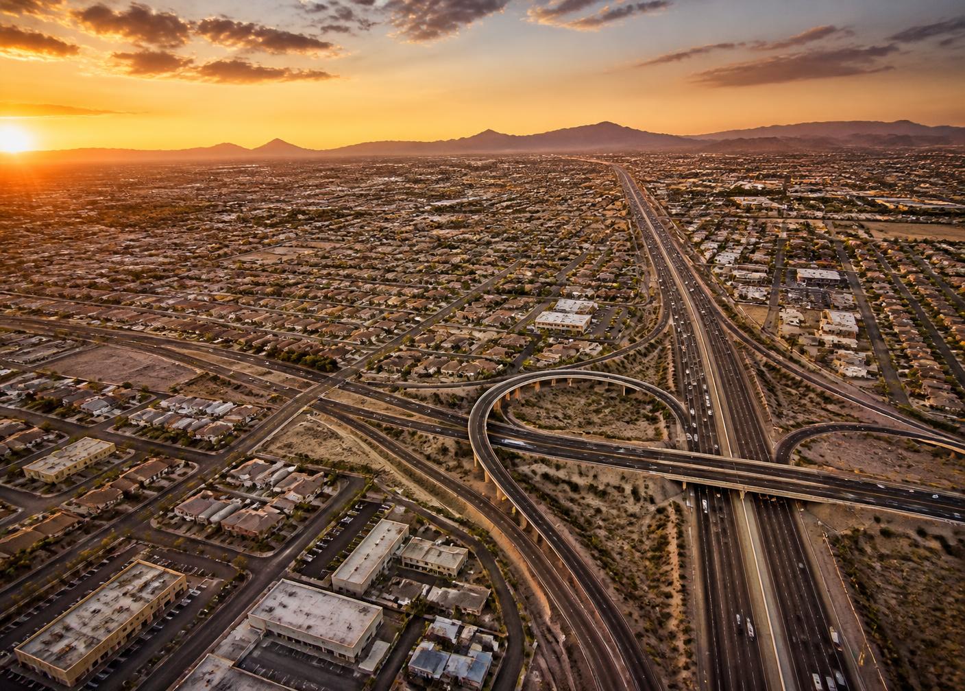 Aerial view of Glendale at sunset with the freeway interchange and desert mountains